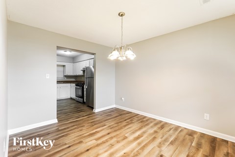 A well-lit, spacious room with wooden flooring and a chandelier hanging from the ceiling.