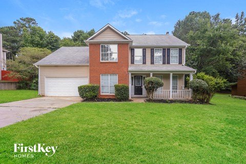 A house with a red brick facade and a white garage door is for sale.