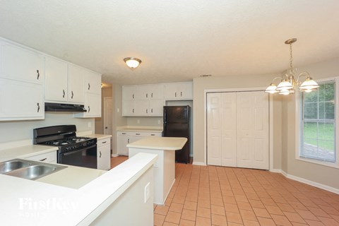 A kitchen with white cabinets and a black stove top oven.