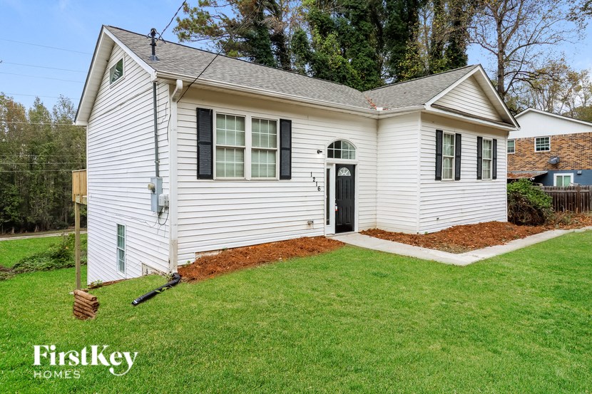 a white house with a lawn and a black door