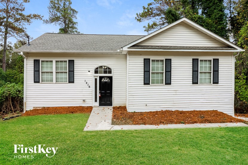 the front view of a white house with black shutters and a lawn