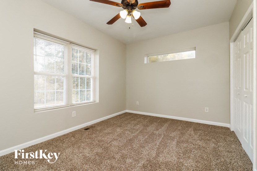the master bedroom has carpet and a ceiling fan
