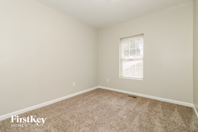 a bedroom with a window and a carpeted floor
