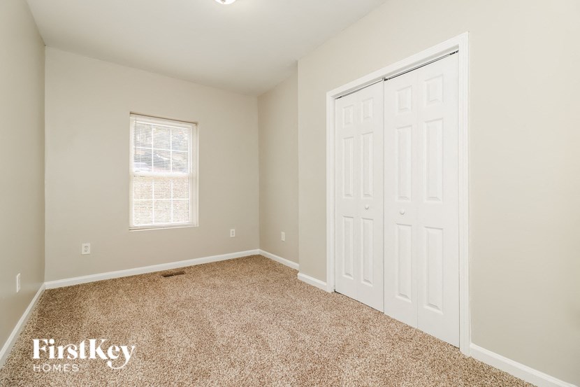 a bedroom with two closets and a window and a carpeted floor