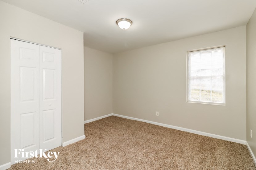 a bedroom with carpet and a white door and window