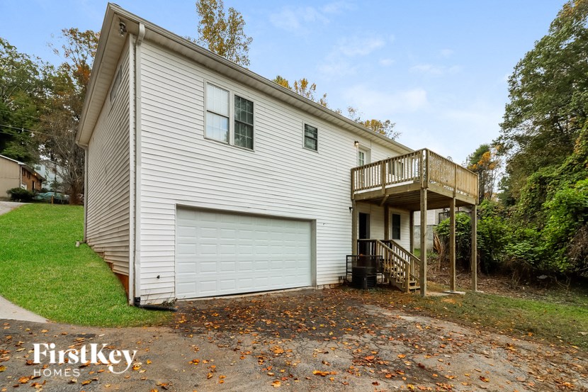 the front of a white house with a garage and a deck