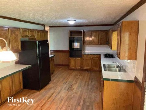 A kitchen with wooden cabinets and a black refrigerator.