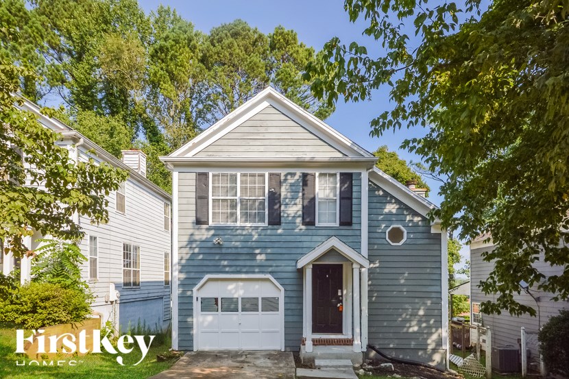 A blue house with a white garage door is for sale.