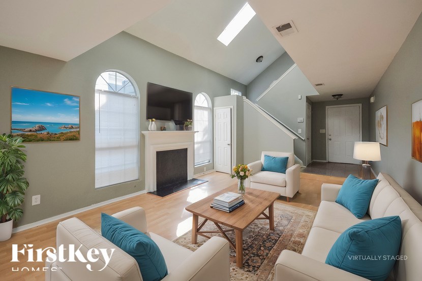A living room with a fireplace and a painting of a beach scene on the wall.