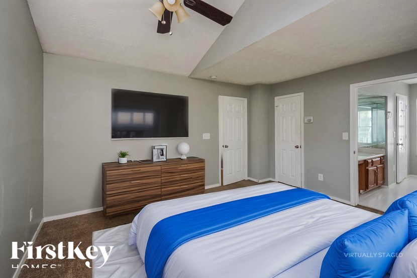 A bedroom with a bed, dresser, and ceiling fan.