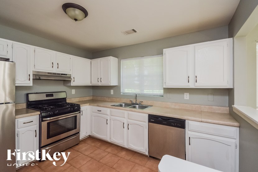 A kitchen with white cabinets and a stove top oven.