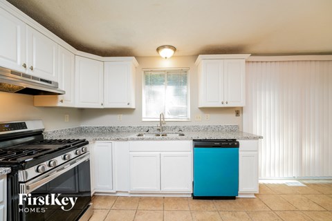 A kitchen with a blue dishwasher and white cabinets.