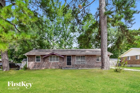 a small brick house with a lawn and trees