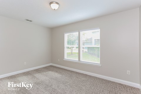 a bedroom with two windows and a carpeted floor