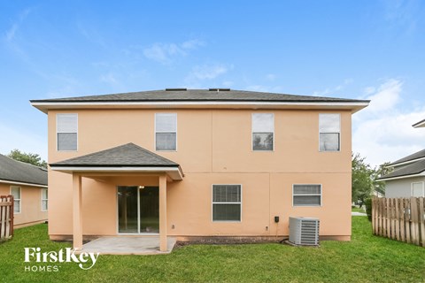 a peach house with a grassy yard and a blue sky