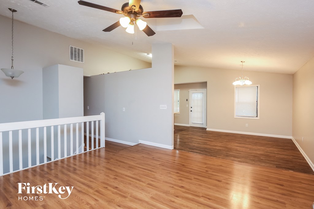 A spacious room with wooden floors and a ceiling fan.