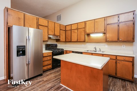 A kitchen with wooden cabinets and a stainless steel refrigerator.