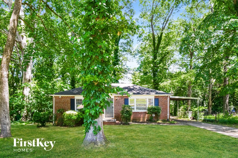 a small brick house with a large tree in front of it