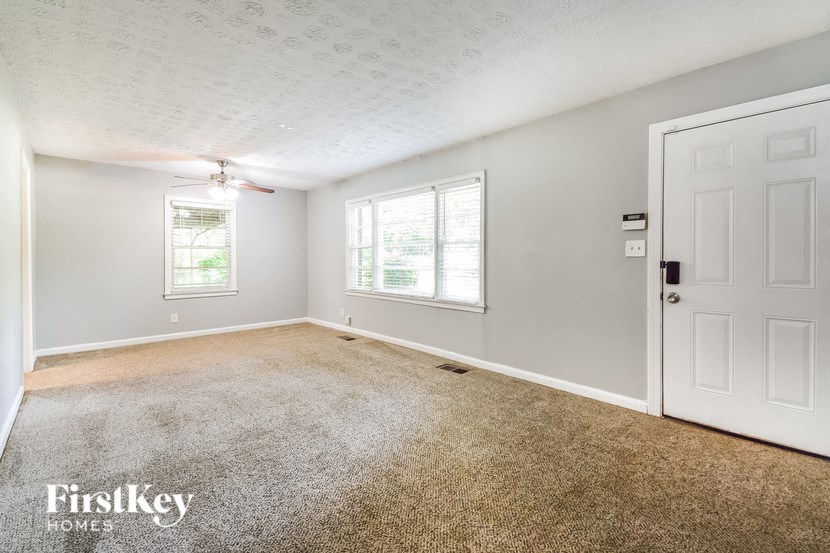 an empty living room with a white door and a ceiling fan
