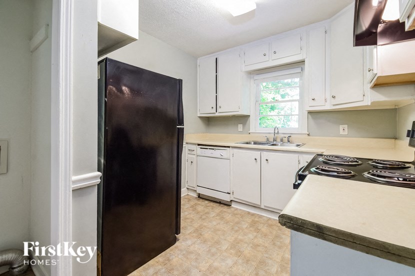 a kitchen with white cabinets and a black refrigerator