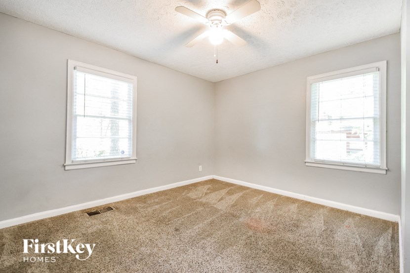 an empty room with two windows and a ceiling fan