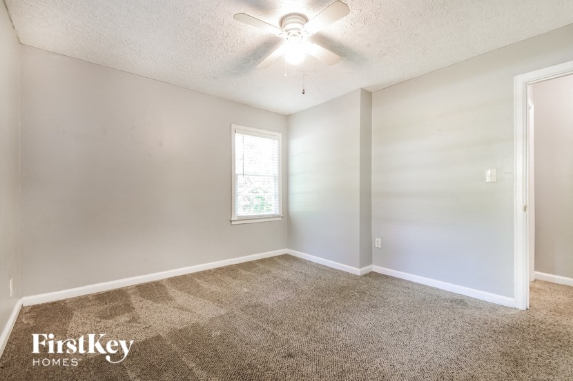 an empty living room with a ceiling fan and a window