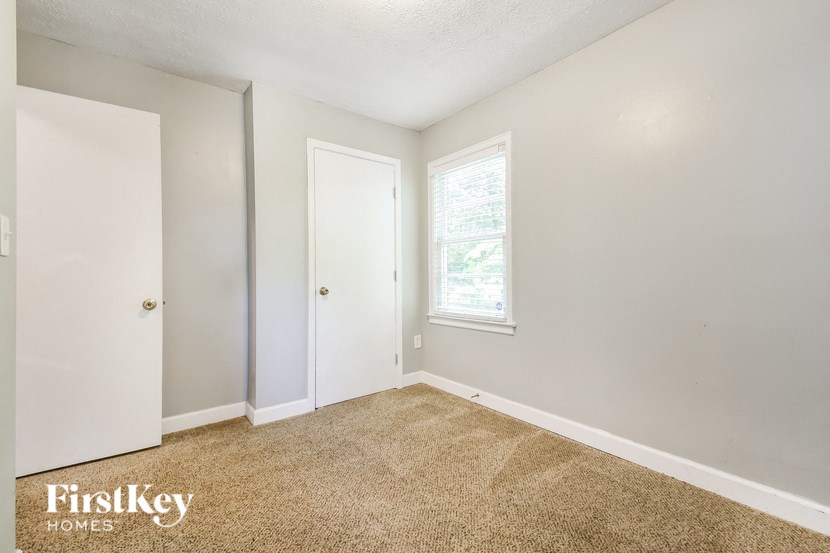 a bedroom with white walls and carpet and a window