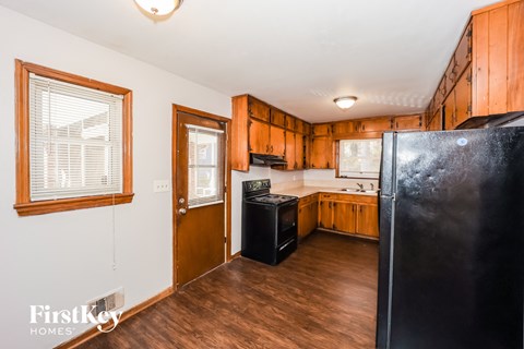 A kitchen with wooden cabinets and a black refrigerator.