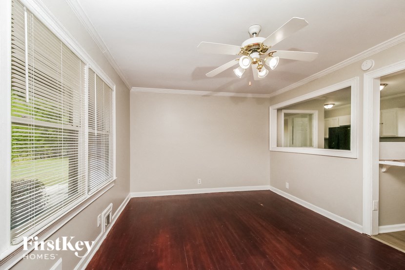 a empty living room with a large window and a ceiling fan