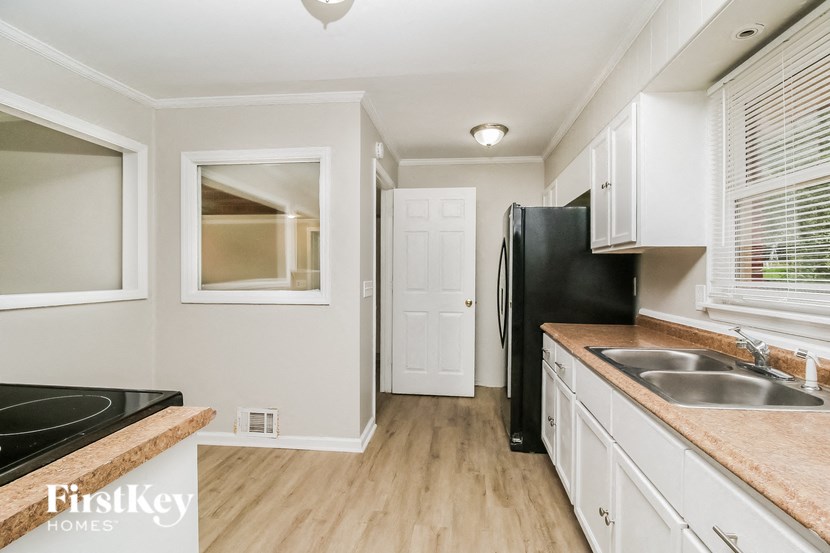 a kitchen with white cabinets and a black refrigerator