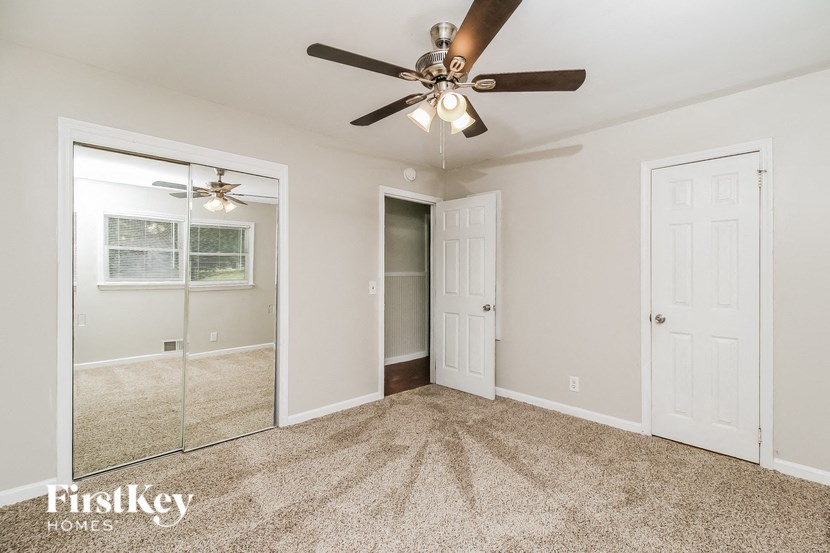 a bedroom with a ceiling fan and a mirror