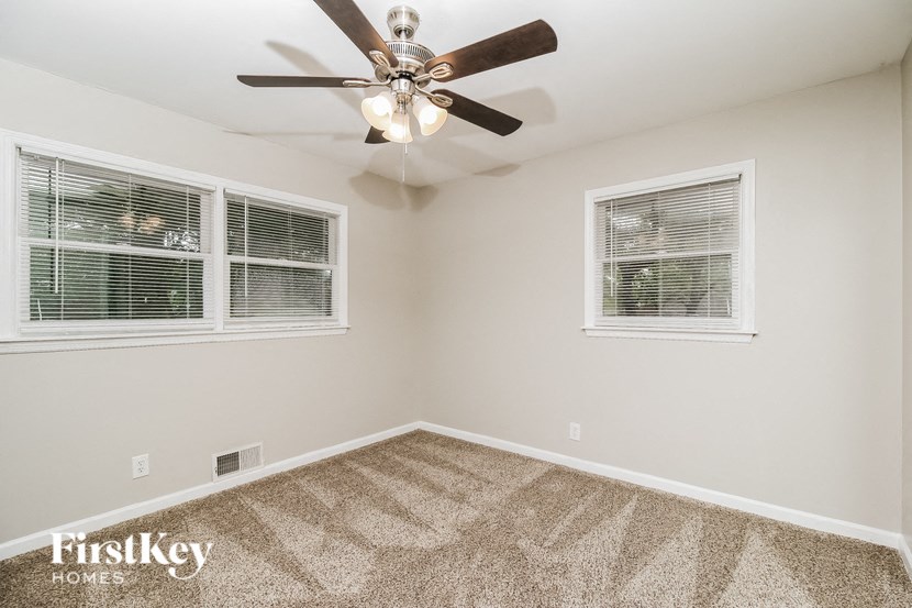 the living room has a ceiling fan and two windows