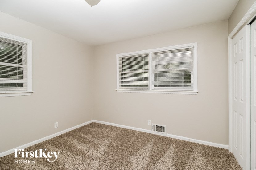 a spacious room with carpet and two windows