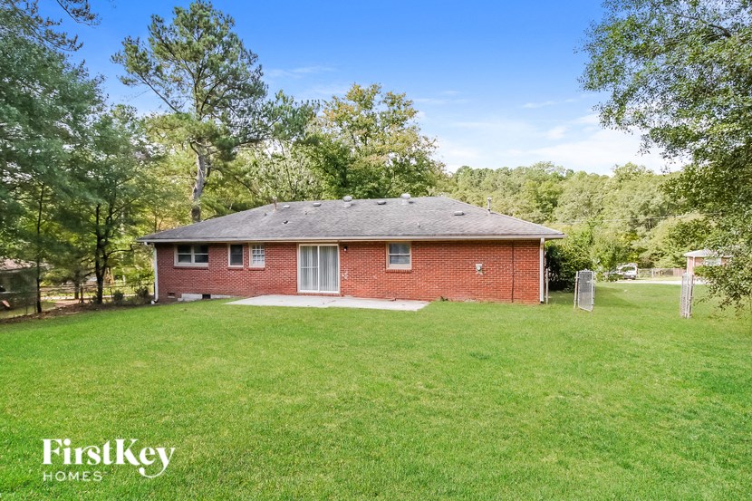 a red brick house with a grassy yard and trees