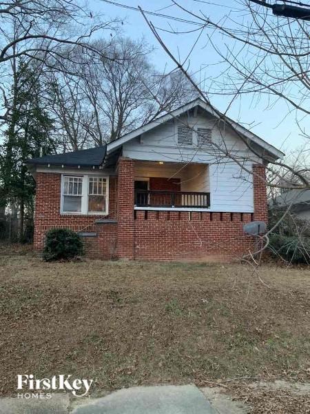 a small brick house with a porch on a field
