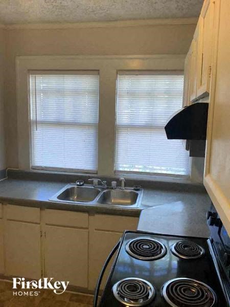 a kitchen with a stove and sink and two windows