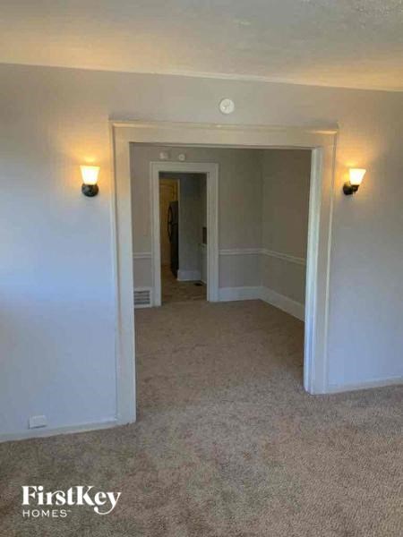 a living room with white walls and a hallway with lights
