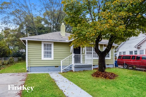 a small green house with a tree in front of it