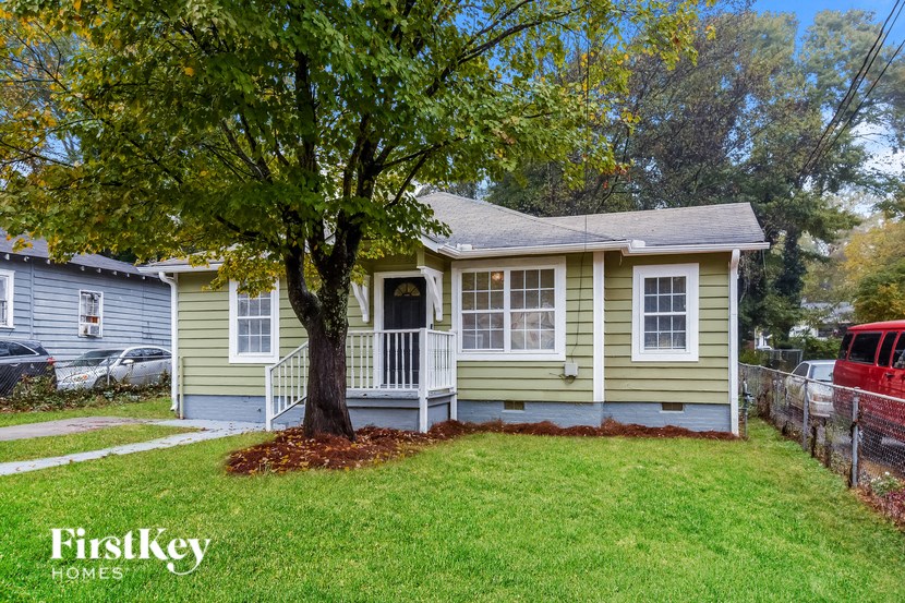 a small yellow house with a tree in the front