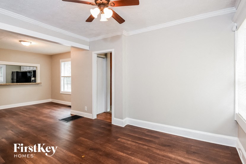 a living room with a ceiling fan and a door to a kitchen