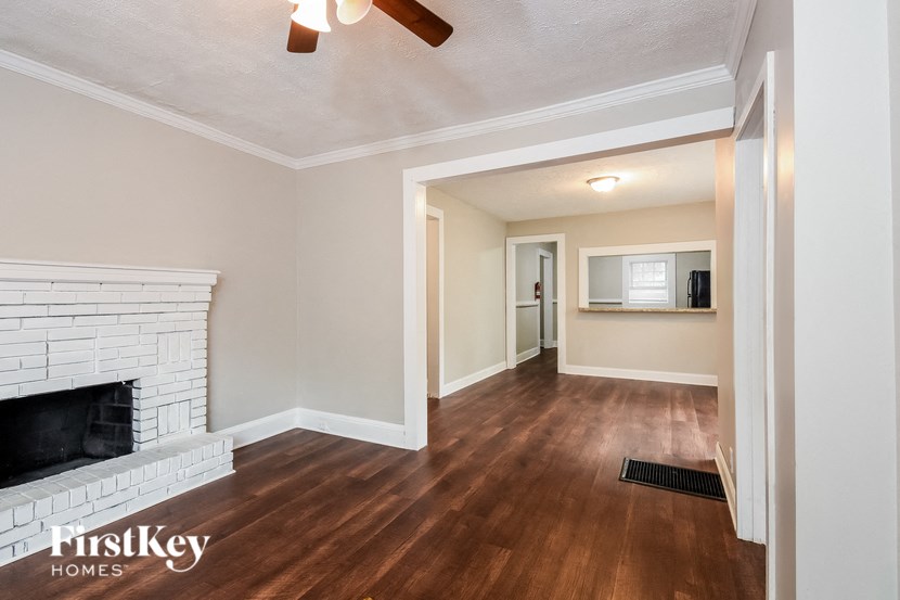 a living room with a white brick fireplace and wood flooring