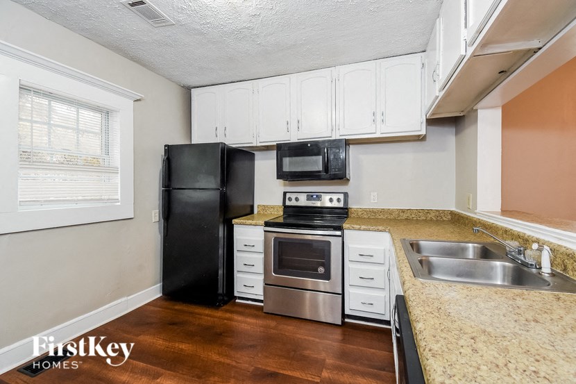a kitchen with white cabinets and a black refrigerator