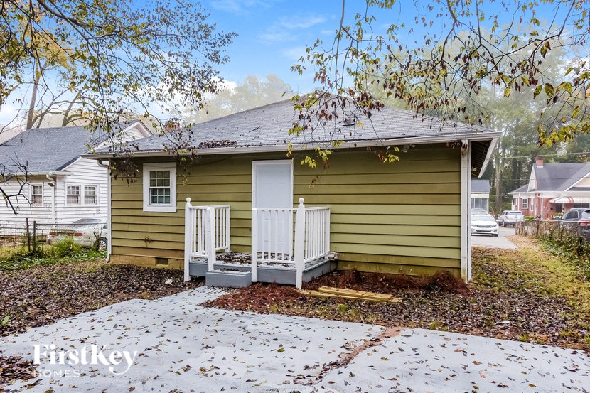 a small yellow house with a porch and a white fence