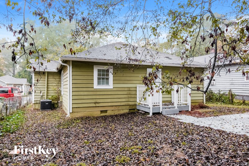 a small yellow house with a white fence