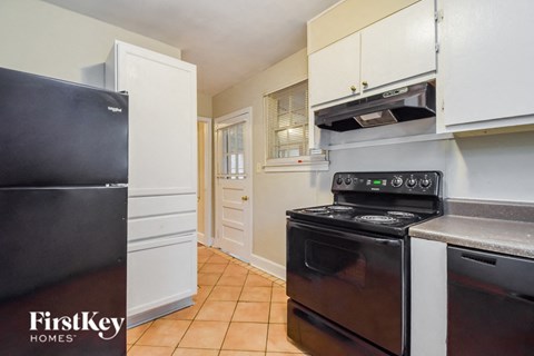 a kitchen with white cabinets and black appliances and a black refrigerator