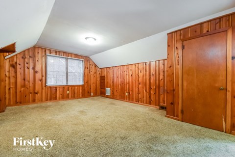 the master bedroom has a carpeted floor and wood paneled walls