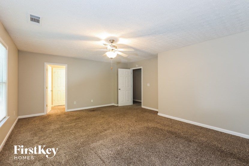 a spacious living room with carpet and a ceiling fan