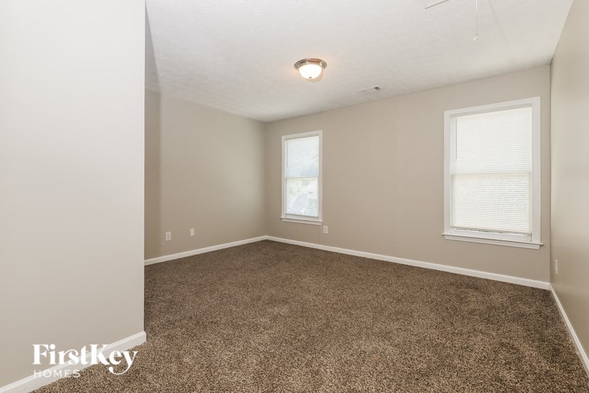 a bedroom with a carpeted floor and two windows