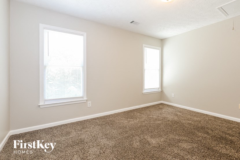 a bedroom with carpet and two windows