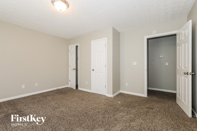 a bedroom with a carpeted floor and a door to a closet